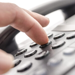 Zoomed in picture of a finger pressing a number on an office phone