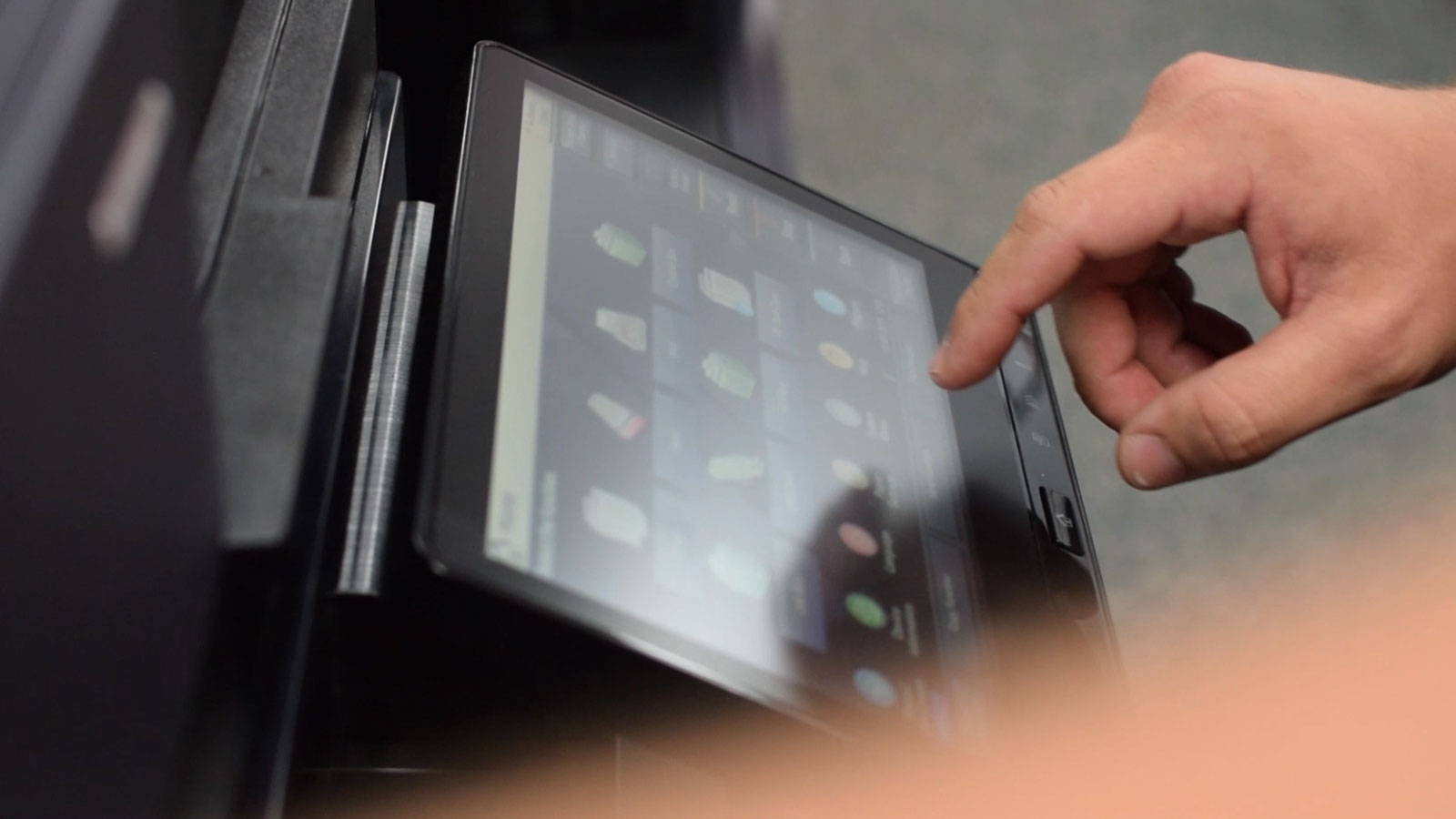 The hand of someone using the touchscreen of a copier